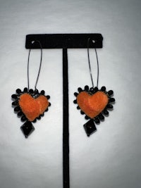 a pair of earrings with orange and black hearts