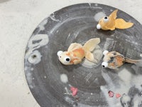 three goldfish on a plate with paint on it