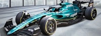 a green racing car is parked in front of a building