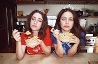 two young women eating cereal in front of a kitchen