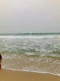 a man standing on a beach with a surfboard
