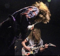 a man with long hair playing a guitar on stage