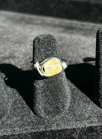 a silver ring with a yellow stone on it