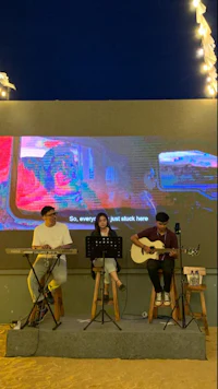 a group of people playing music on stage in front of a large screen