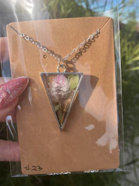 a person holding a necklace with dried flowers in it