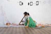 a woman in a green dress sitting on the floor