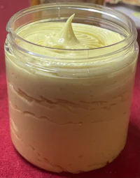 a jar of yellow butter sitting on a red table