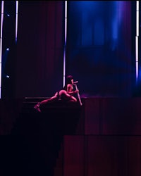 a woman laying on a stage in front of a neon light