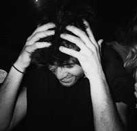 a black and white photo of a man with his hands on his head