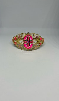 a gold and pink brooch with a cross on it