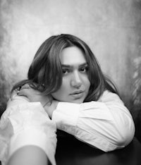 a black and white photo of a woman leaning on a table