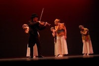 a group of dancers on stage with a violin