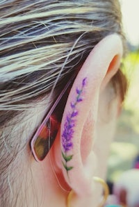 a woman with a purple flower tattoo on her ear