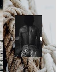 a black and white photo of a man sitting on a rope