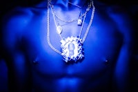 a man in a blue shirt with a necklace on his chest