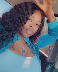 a woman in a blue top is posing in the back seat of a car