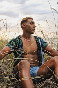 a man sitting on a surfboard in a field of tall grass