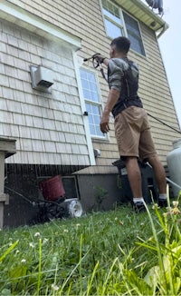 a man spraying a house with a pressure washer