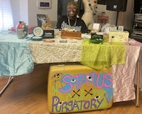 a woman sits at a table with a sign on it
