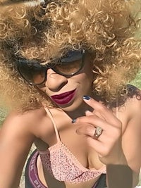 a woman in a bikini and sunglasses taking a selfie