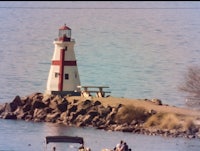 a lighthouse sits on a rock in the water