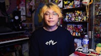 a young man in a black shirt standing in front of a toy room
