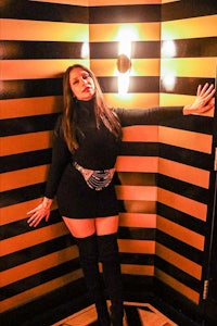 a woman in a black dress leaning against a wall