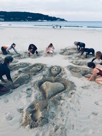 a group of people making sand sculptures on the beach