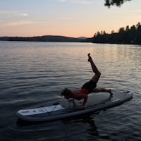 a woman doing a yoga pose on a stand up paddle board