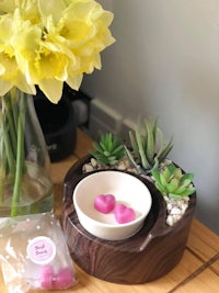 a wooden bowl with succulents and daffodils on it