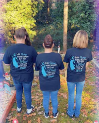 four women wearing black t - shirts in front of a grave