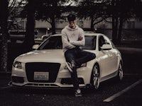 a man posing in front of a white car