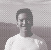 a man in a white shirt standing in front of a mountain