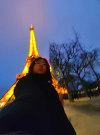a woman is taking a selfie in front of the eiffel tower