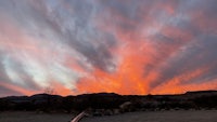 a sunset over a lake with mountains in the background