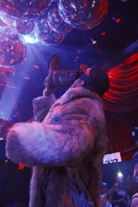 a man in a fur coat standing up in a club