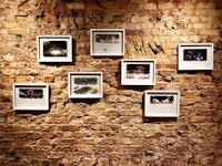 a group of framed pictures hanging on a brick wall