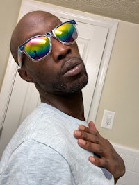 a black man wearing a pair of rainbow colored sunglasses