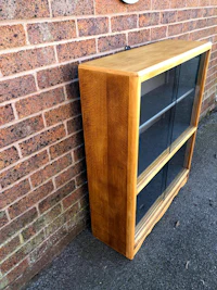a wooden bookcase leaning against a brick wall
