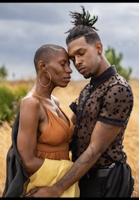 a man and woman standing in a field with dreadlocks