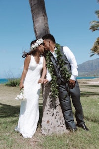 a bride and groom kiss in front of a palm tree