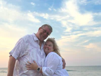 a man and woman hugging on the beach at sunset