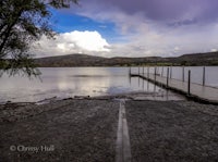 a dock on a lake with a cloudy sky