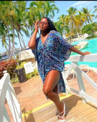 a woman in a blue kaftan standing next to a pool