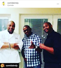 three men are posing for a picture in front of a kitchen