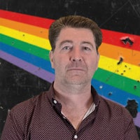 a man standing in front of a rainbow flag