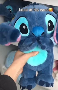 a person is holding a stitch stuffed animal
