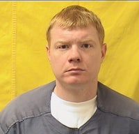 a man in a blue shirt is standing in front of a yellow wall