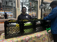 two people standing at a table with crates of food