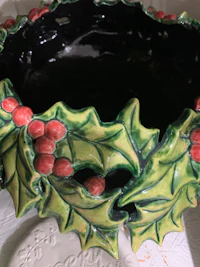 a bowl with holly leaves and berries on it